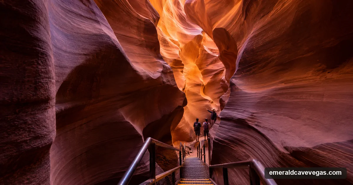 The swirling sandstone walls of Lower Antelope Canyon with a steel staircase and two visitors with a guide